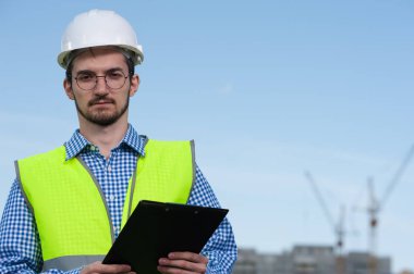 Planlı Yeşil Yelekli Genç Mühendis Portresi