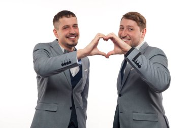Two young funny men in formal clothes show heart