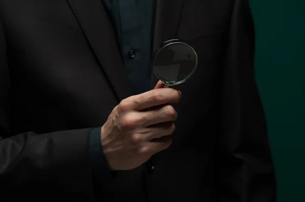 Man holding a magnifier and a business card