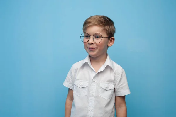 Zabawny mały biały chłopiec w okularach na niebieskim tle. — Zdjęcie stockowe