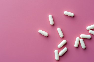 Close-up of white pills lie on a pink surface