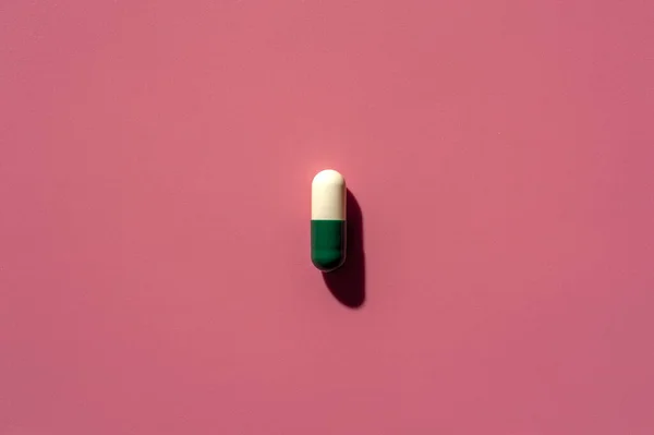 Close-up of one pill lies on a pink surface — Stock Photo, Image