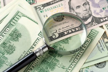 Büyüteç etrafa saçılmış doların üstünde