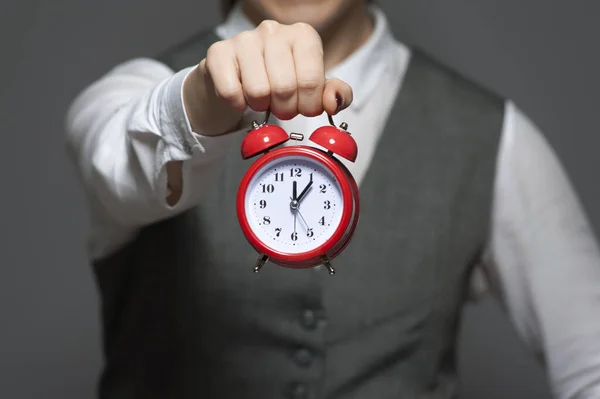 Close-up of young businesswoman or office worker holding red clock in hands