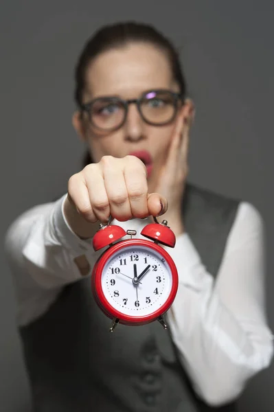 Nervoso feminino trabalhador de escritório segurando relógio vermelho — Fotografia de Stock