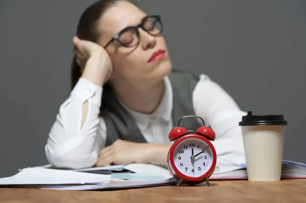 Fáradt irodai dolgozó az asztalnál papírokkal és piros ébresztőórával — Stock Fotó