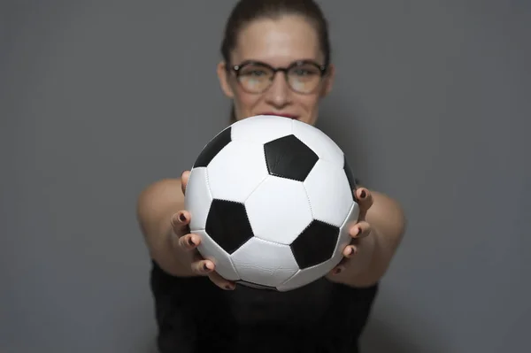 Young charming woman football fan or player holding soccer ball in hands