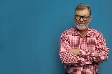 Kollarını göğsünde birleştiren kendinden emin yaşlı bir adamın portresi.