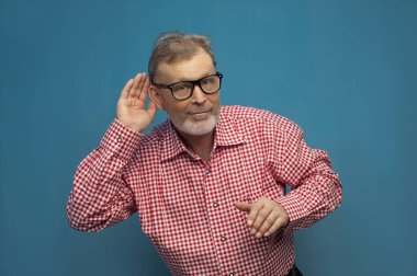 Yakışıklı, komik, yaşlı bir adam, şık bir tarz ve gözlük takıyor.