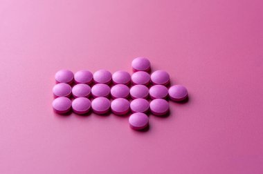 Pembe hapların yakın çekimi pembe bir yüzeye uzanıyor.