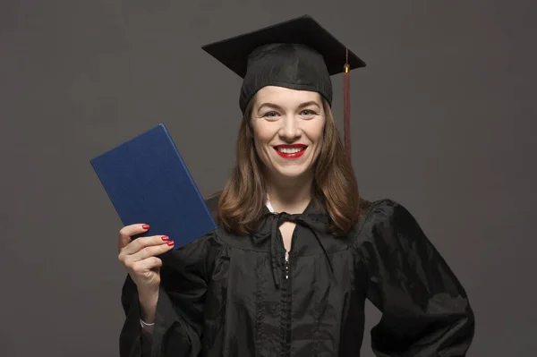 Graduate female student with stubble in eyeglasses wearing black mantle — Stock Photo, Image