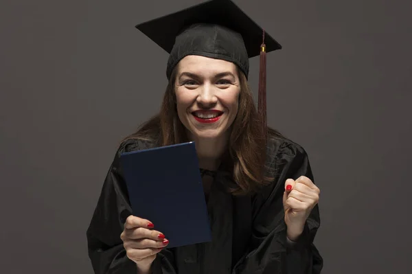 Graduate female student with stubble in eyeglasses wearing black mantle — Stock Photo, Image