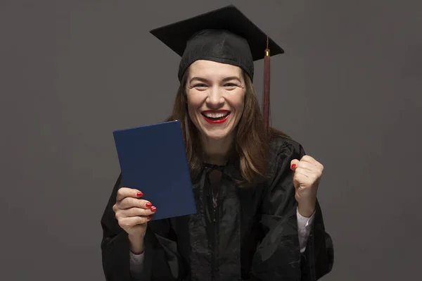 Graduate female student with stubble in eyeglasses wearing black mantle — Stock Photo, Image