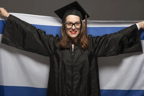 Charming female student smiling in eyeglasses wearing black mantle — Stock Photo, Image