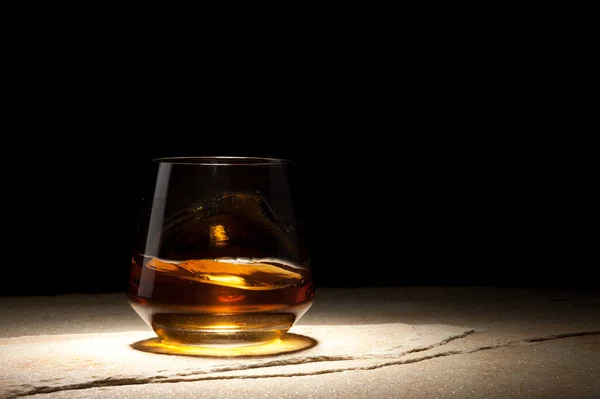 Half vol glas whisky staat op een donkere tafel. — Stockfoto