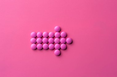 Pembe hapların yakın çekimi pembe bir yüzeye uzanıyor.