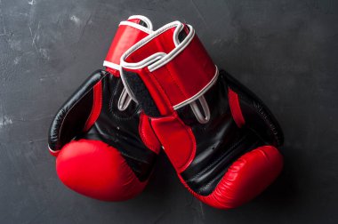 Kırmızı boks eldivenleri gri duvarda asılı.