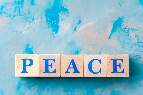 Wooden cubes with word PEACE on blue table. — Stock Photo, Image