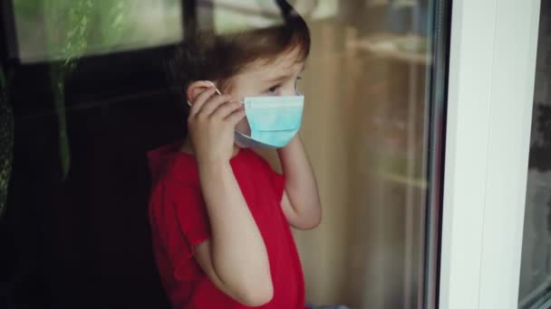 Retrato de niño pequeño con mascarilla médica mirando a la cámara. Niño varón triste quitarse la máscara protectora del virus en el interior. Concepto de vida de salud y seguridad a partir del coronavirus y la pandemia. De cerca. — Vídeos de Stock