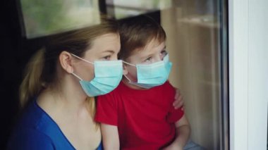 Coronavirus. Hasta anne ve oğlu pencereden dışarı bakıyor ve Coronavirus veya Cvid-19 'dan maske takıyor ve iyileşiyor.