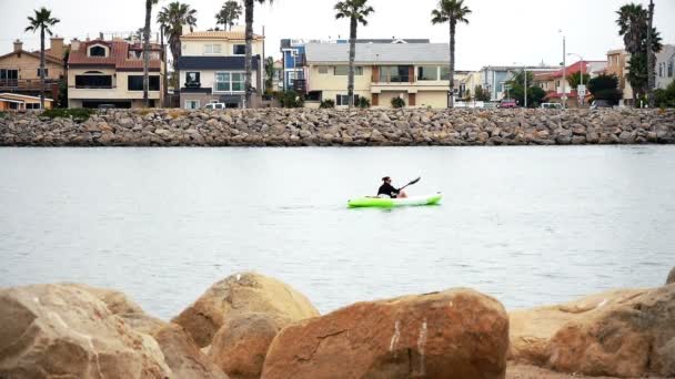 PORT HUENEME, CA U.S.A - JUNE 2015: Single female kayaker paddles in harbor on overcast morning. — Stock Video