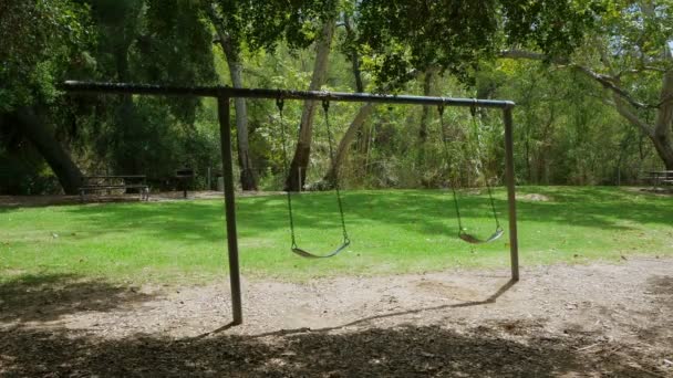 Opuszczony Swingset w parku poruszają się swobodnie — Wideo stockowe