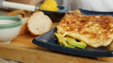 Birisi restoranda sebzeli omlet, salata ve avokado yiyor. Bir tabakta çırpılmış yumurta. Lezzetli. Yakın plan