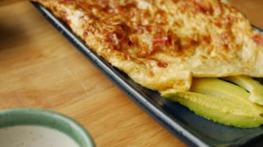 Restoranda sebzeli omlet, salata ve avokado. Bir tabakta çırpılmış yumurta. Lezzetli. Yakın plan
