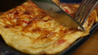 Birisi restoranda sebzeli omlet, salata ve avokado yiyor. Bir tabakta çırpılmış yumurta. Lezzetli. Yakın plan