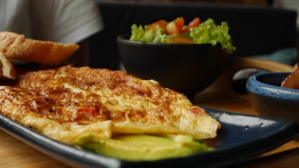 Omelette aux légumes, salade et avocat au restaurant. Des œufs brouillés dans une assiette. Délicieux. Gros plan — Video