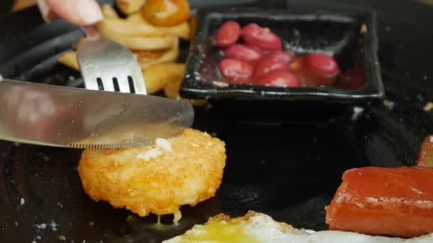 Vrouw eet traditioneel Engels ontbijt met gebakken eieren, worstjes, rode bonen, hash browns, champignons en tomaten. Close-up — Stockvideo