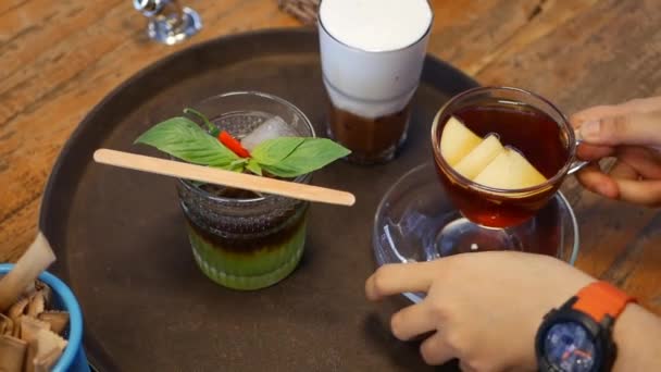 Female waiter is putting cups of tea and coffee on a round tray and prepares an order for customers in cafe hall — Stock Video