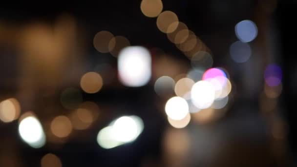 Όμορφη λαμπερή bokeh σε σκούρο θολή φόντο τη νύχτα. Το στρογγυλό πολύχρωμο bokeh λάμψη από τα φώτα των αυτοκινήτων σε μποτιλιάρισμα στο δρόμο της πόλης. Εκτός εστίασης με θολή εικόνα. Μη εστιασμένα φώτα της πόλης. Κυκλοφορία — Αρχείο Βίντεο