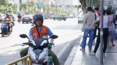 Motorcycle taxi driver is waiting for a passenger at a bus stop. BANGKOK, THAILAND - DECEMBER 02, 2019