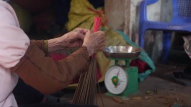 Vietnamlı kadın, mağazalara sevkiyat için yeni yapılmış tütsü çubuklarını tartıyor, paketliyor ve çıkarıyor. Asya 'da tütsü üretimi. Geleneksel sanat ve kültür konsepti