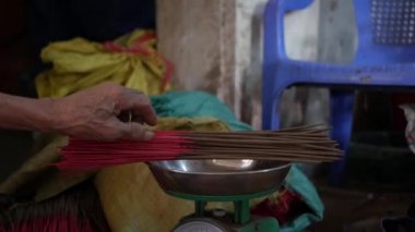 Vietnamlı kadın, mağazalara sevkiyat için yeni yapılmış tütsü çubuklarını tartıyor, paketliyor ve çıkarıyor. Asya 'da tütsü üretimi. Geleneksel sanat ve kültür konsepti