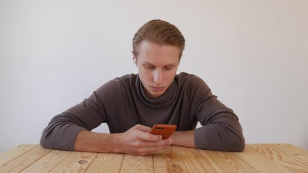 Guapo joven utiliza un teléfono inteligente, escribe un mensaje, charlando, buscando información en el teléfono. Primer plano. 4k — Vídeos de Stock