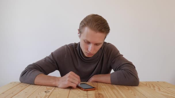 Guapo joven utiliza un teléfono inteligente, escribe un mensaje, charlando, buscando información en el teléfono. Primer plano. 4k — Vídeos de Stock