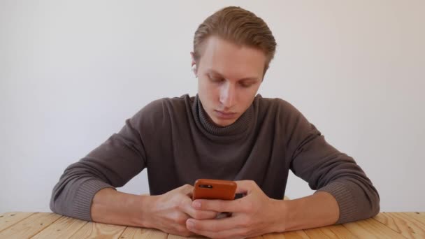 Jóképű fiatalember okostelefont használ, üzenetet ír, cseveg, információt keres a telefonban. Közelkép. 4k — Stock videók