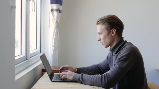 Młody człowiek freelancer za pomocą laptopa, pisanie na maszynie, przewijanie, surfing web, patrząc na ekranie. Profesjonalne, kreatywne tysiąclecie, pracujące przy jego biurku w pracowni biurowej. Student uczący się online. 4k — Wideo stockowe