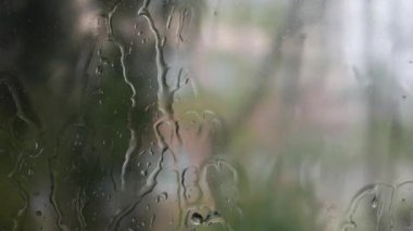 Şiddetli yağmur suyu pencere camlarına ve akıntıya karşı akar. Yakın plan. Yağmur mevsiminde cam zemin üzerinde yağmur damlaları. 4k