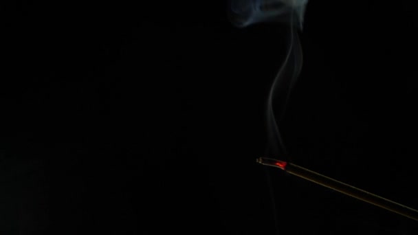 Nahaufnahme von brennenden Räucherstäbchen. Rauch weht vom Ende des heißen Sommers. Duft, der von Weihrauch auf schwarzem Hintergrund ausgeht. Entspannung, Meditation und Aromatherapie — Stockvideo