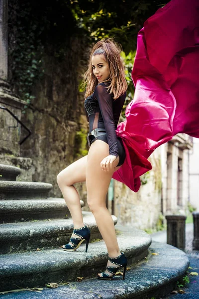 Fille en robe noire serrée et grand tissu rouge — Photo