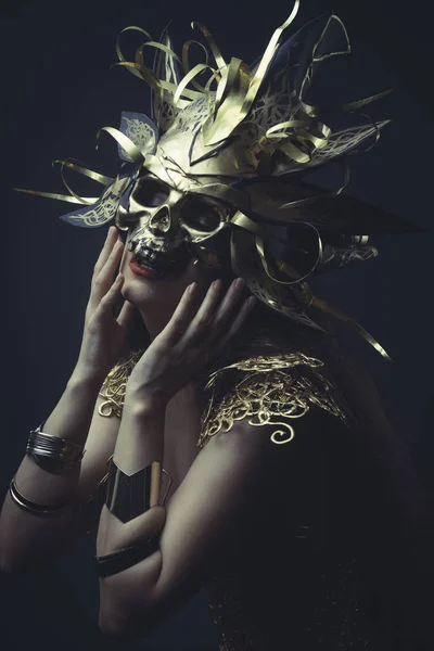 Meisje in gouden jurk en masker — Stockfoto