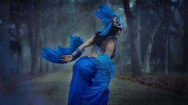 Mavi kablolar, ayıların kuş kanatları ve renkli miğferlerden oluşan takım elbiseli güzel, gotik esmer kız.