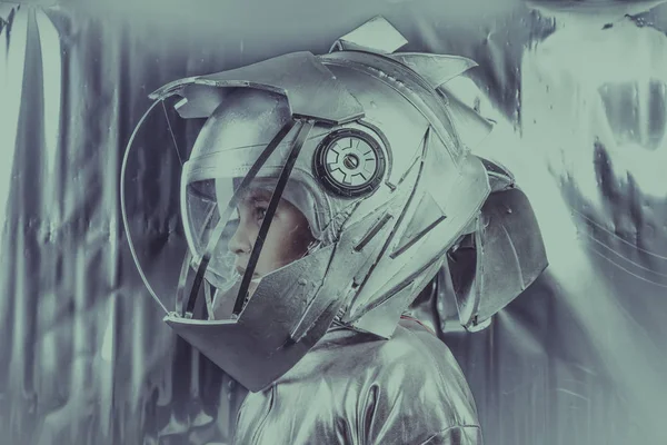 男孩扮演一个宇航员与空间头盔和金属西装超过银色背景 — 图库照片