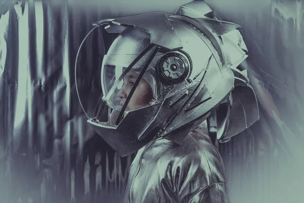 男孩扮演一个宇航员与空间头盔和金属西装超过银色背景 — 图库照片