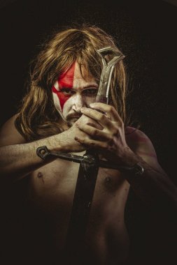 Yüz, uzun saç metal kılıç ve savaş boya ile vahşi savaşçı