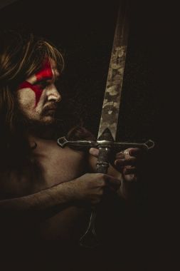 Yüz, uzun saç metal kılıç ve savaş boya ile vahşi savaşçı