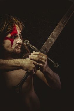 Yüz, uzun saç metal kılıç ve savaş boya ile vahşi savaşçı